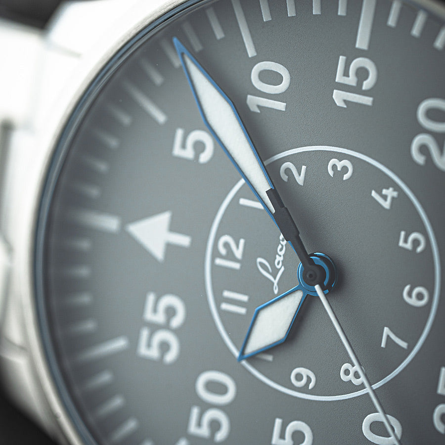 Close-up of a watch face with a gray background and white markings.